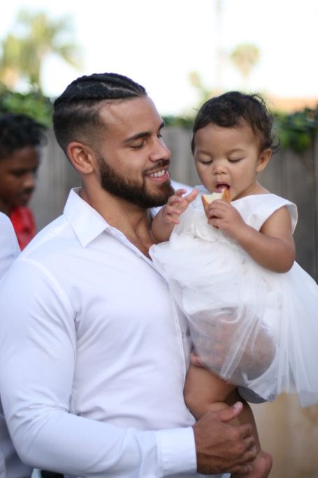 cory and ryder both wearing white outfit, cory holding uo baby ryder who is eating her icecream 